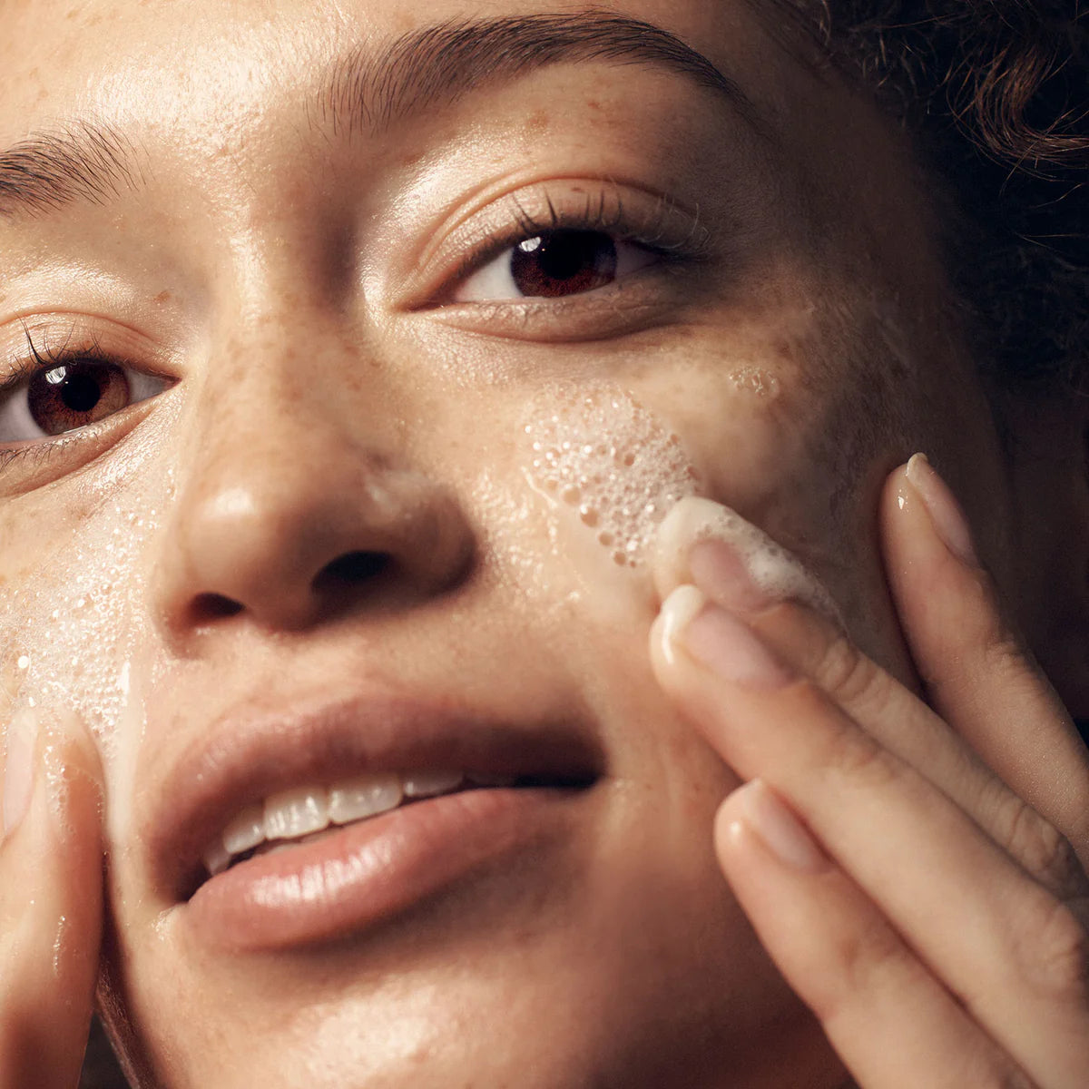Close-up of woman applying philosophy purity facial cleanser foam to her face for gentle cleansing