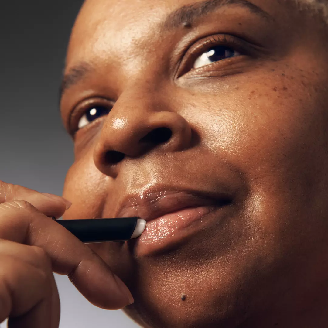 Close-up of a person applying philosophy lip serum to moisturize and soften lips