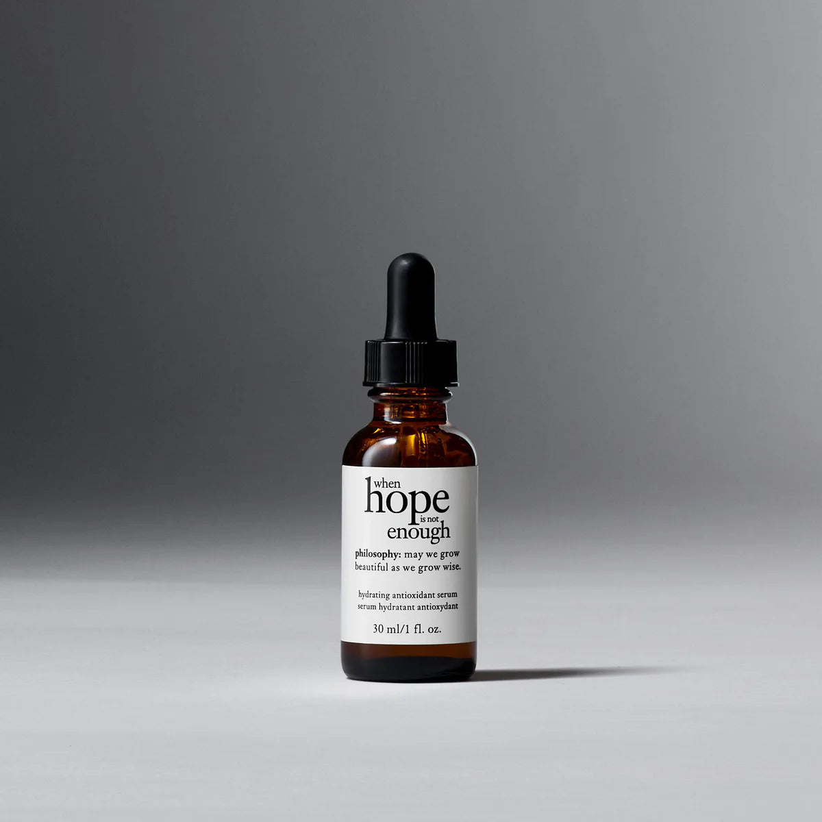 Philosophy facial firming serum in amber glass dropper bottle with white label on gray background