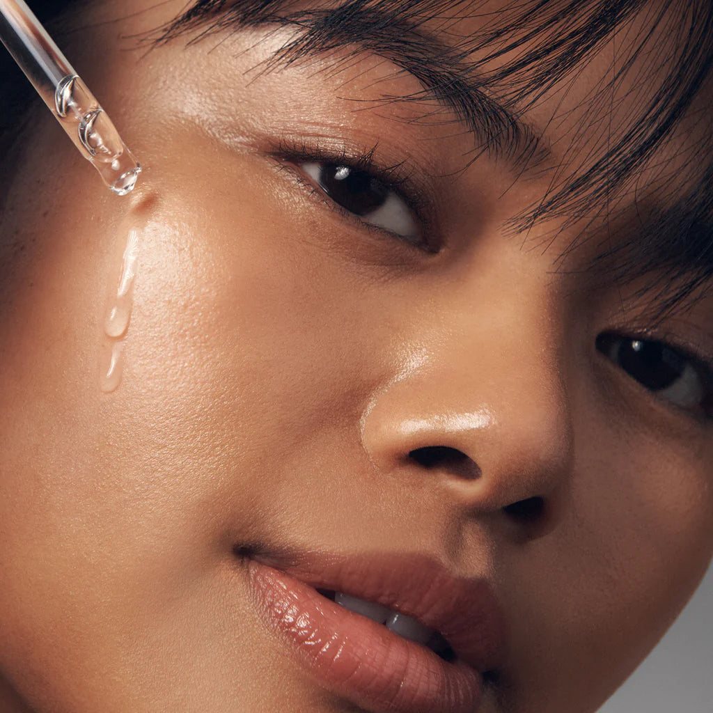 Close-up of woman applying Philosophy facial firming serum with dropper on smooth skin