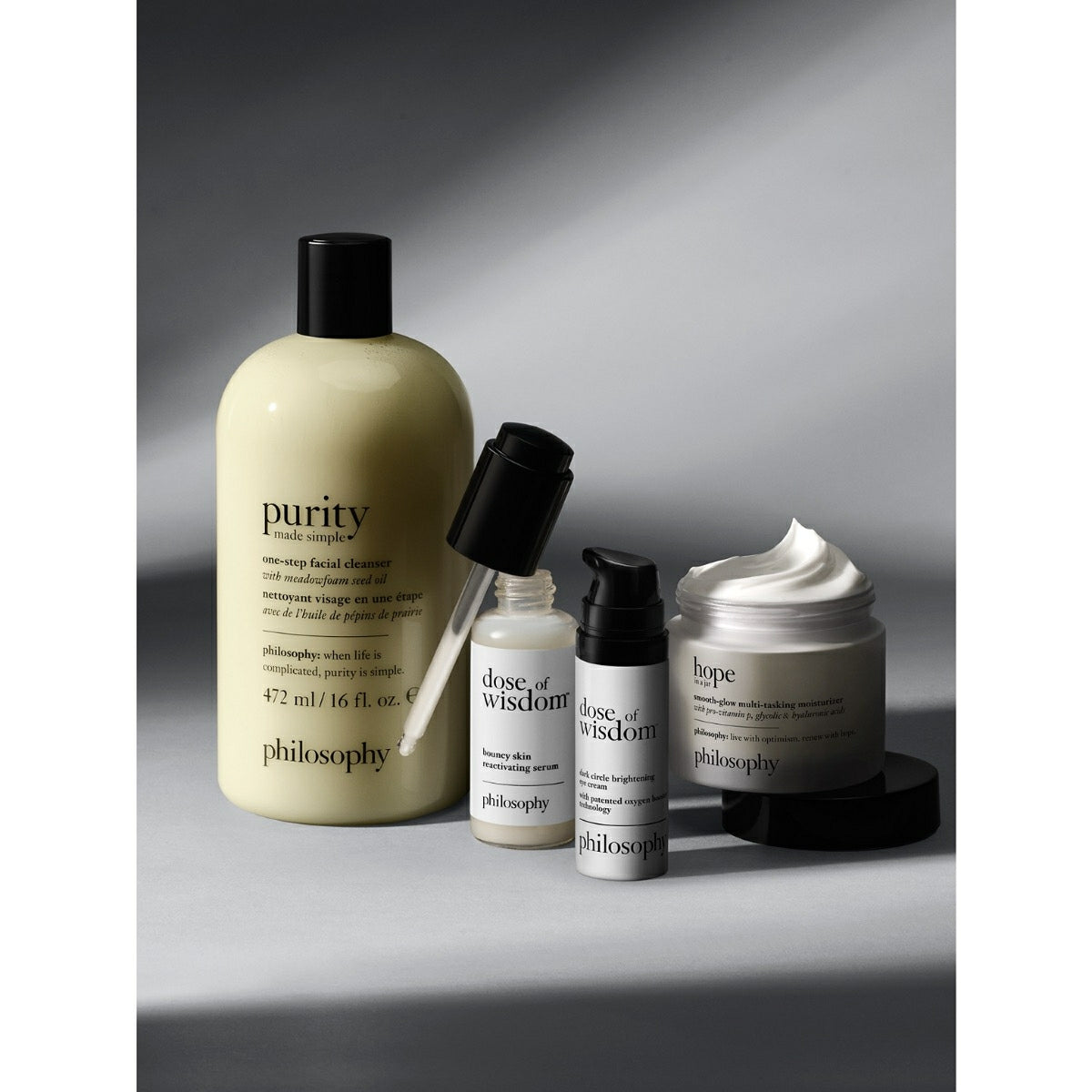 Philosophy skincare set with dark circle brightening eye cream and facial cleanser on gray background