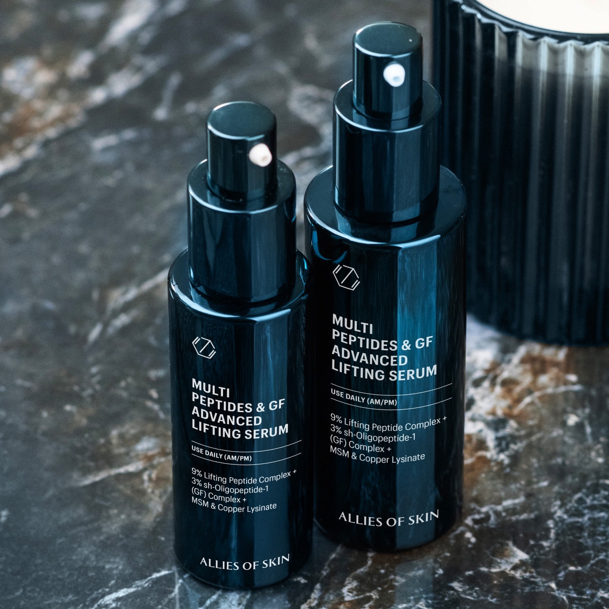 Allies of Skin multi peptide lifting serum duo in sleek navy pump bottles on marble countertop