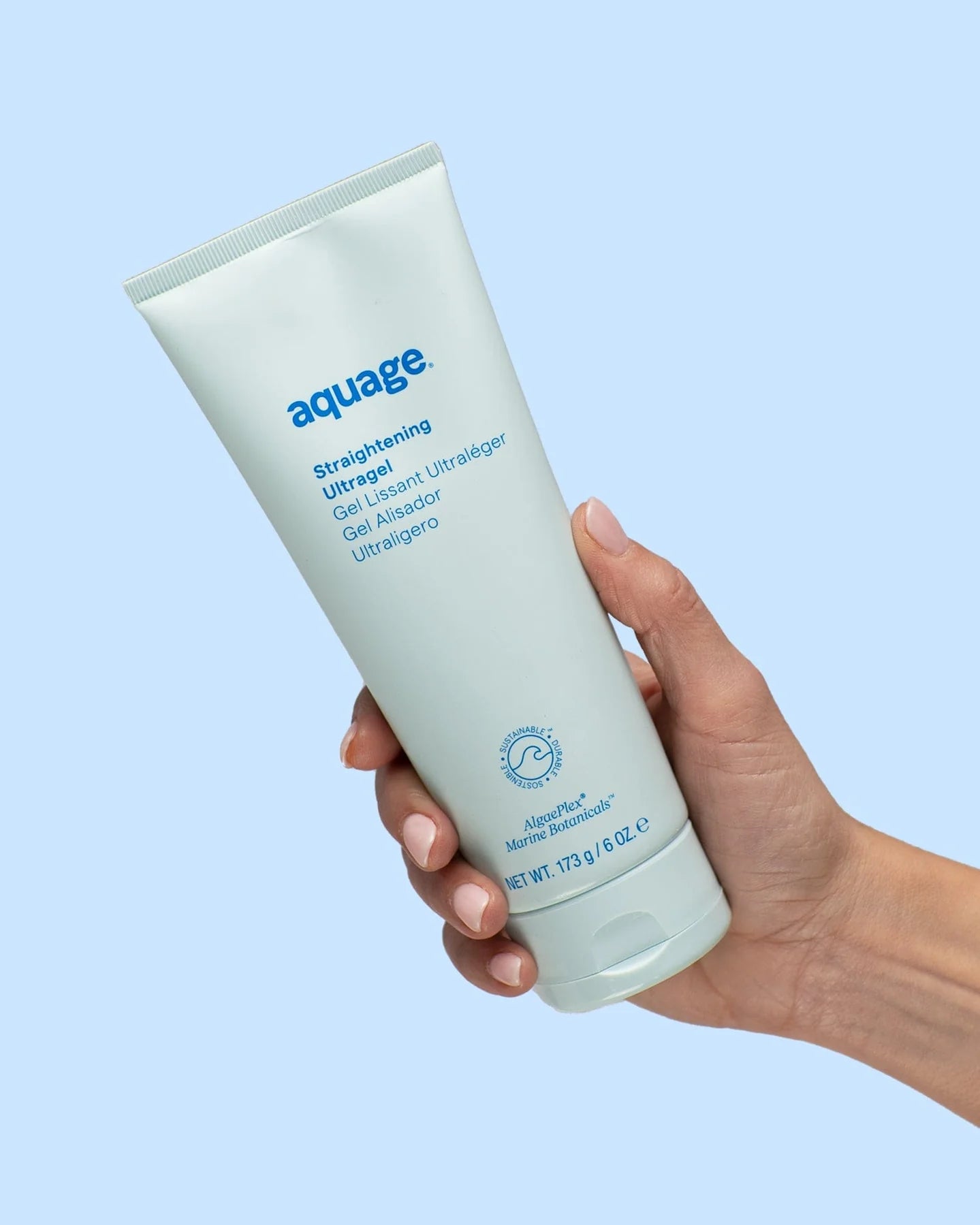 Hand holding Aquage Straightening Ultragel tube with light blue background for hair smoothing