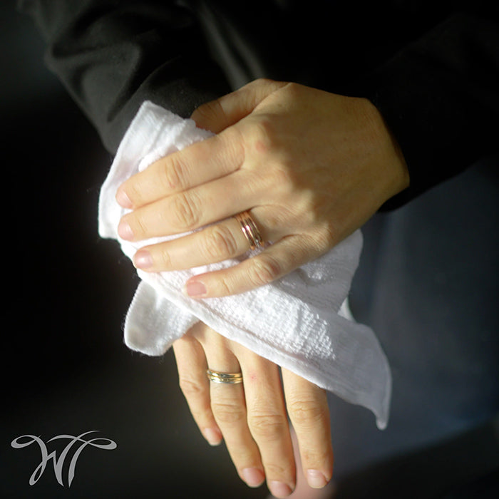 Person using a cotton refreshment towel to gently wipe hands for a fresh feel