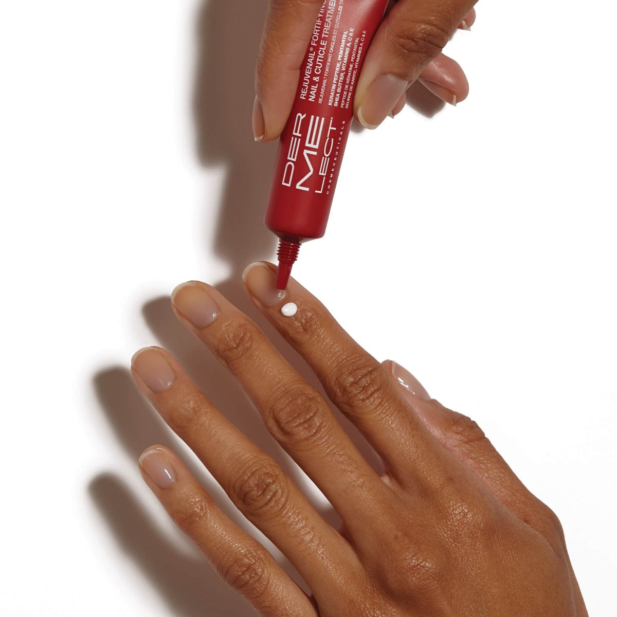 Dermelect red tube applying white cream to fingernails demonstrating nail and cuticle treatment travel size for soft cuticles