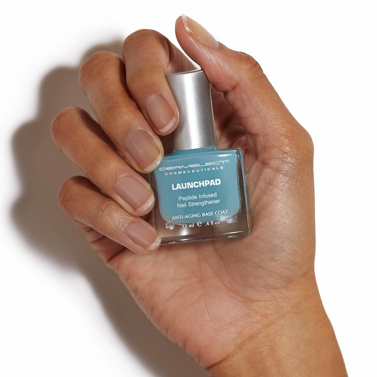 Hand holding Dermelect Launchpad nail strengthener bottle with turquoise peptide infused base coat on white background