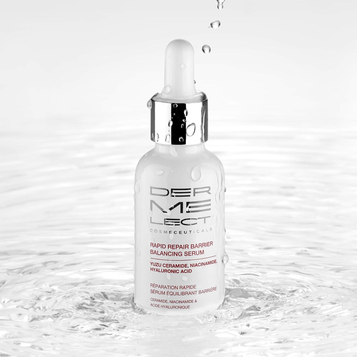 Dermelect Rapid Repair Serum white glass dropper bottle with silver cap reflected in rippling water and droplets