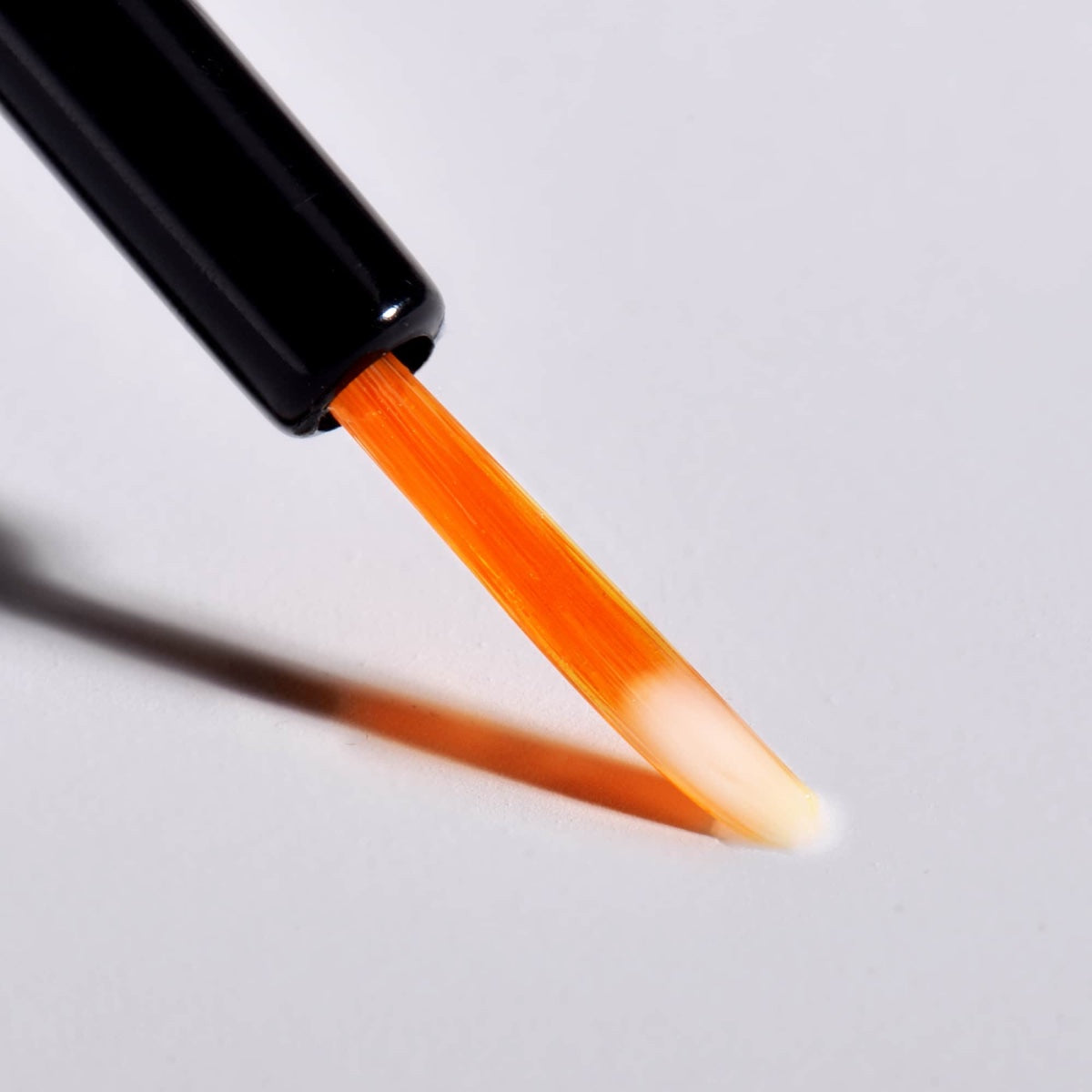 Close up precision applicator brush with orange serum on tip for lashes Dermelect XL Lash Volumizer