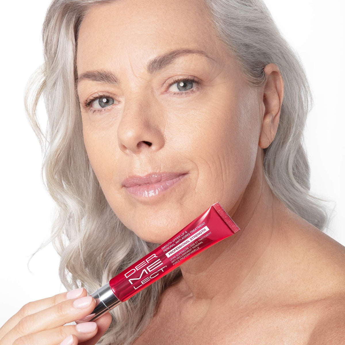 Dermelect upper lip anti-aging cream held by mature woman with silver hair showing smoother upper lip area