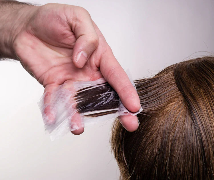 Seki Edge end papers used for hair coloring, showing a hand holding a paper against brown hair