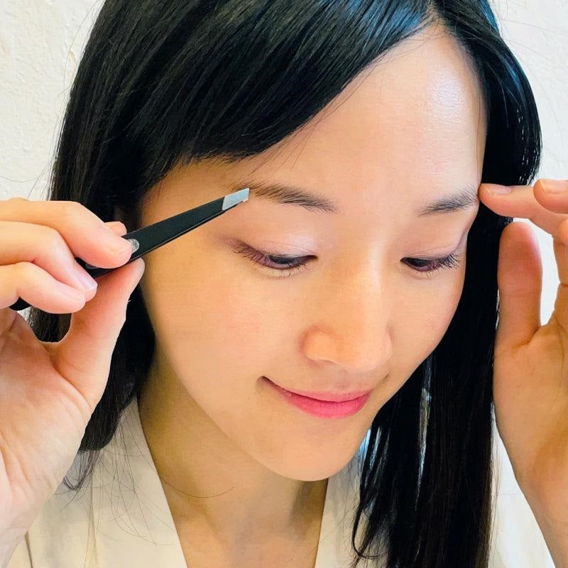 Seki Edge Green Bell tweezers Japan in use for precise eyebrow grooming and shaping
