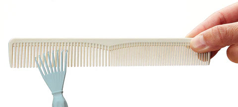 Olivia Garden Comb Cleaner removing hair from a light beige comb held by a hand