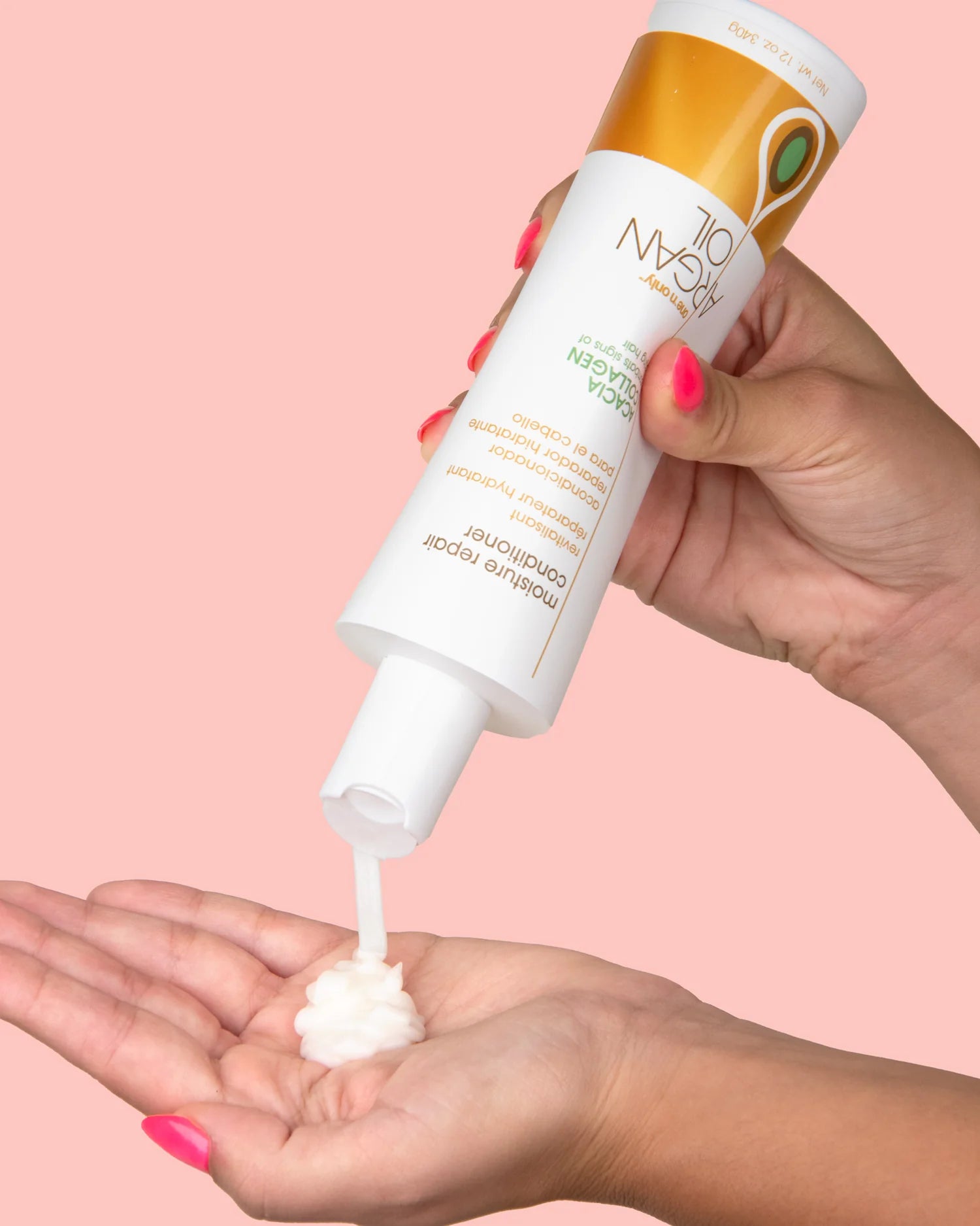 One N Only moisture repair conditioner being dispensed onto a hand with pink nails