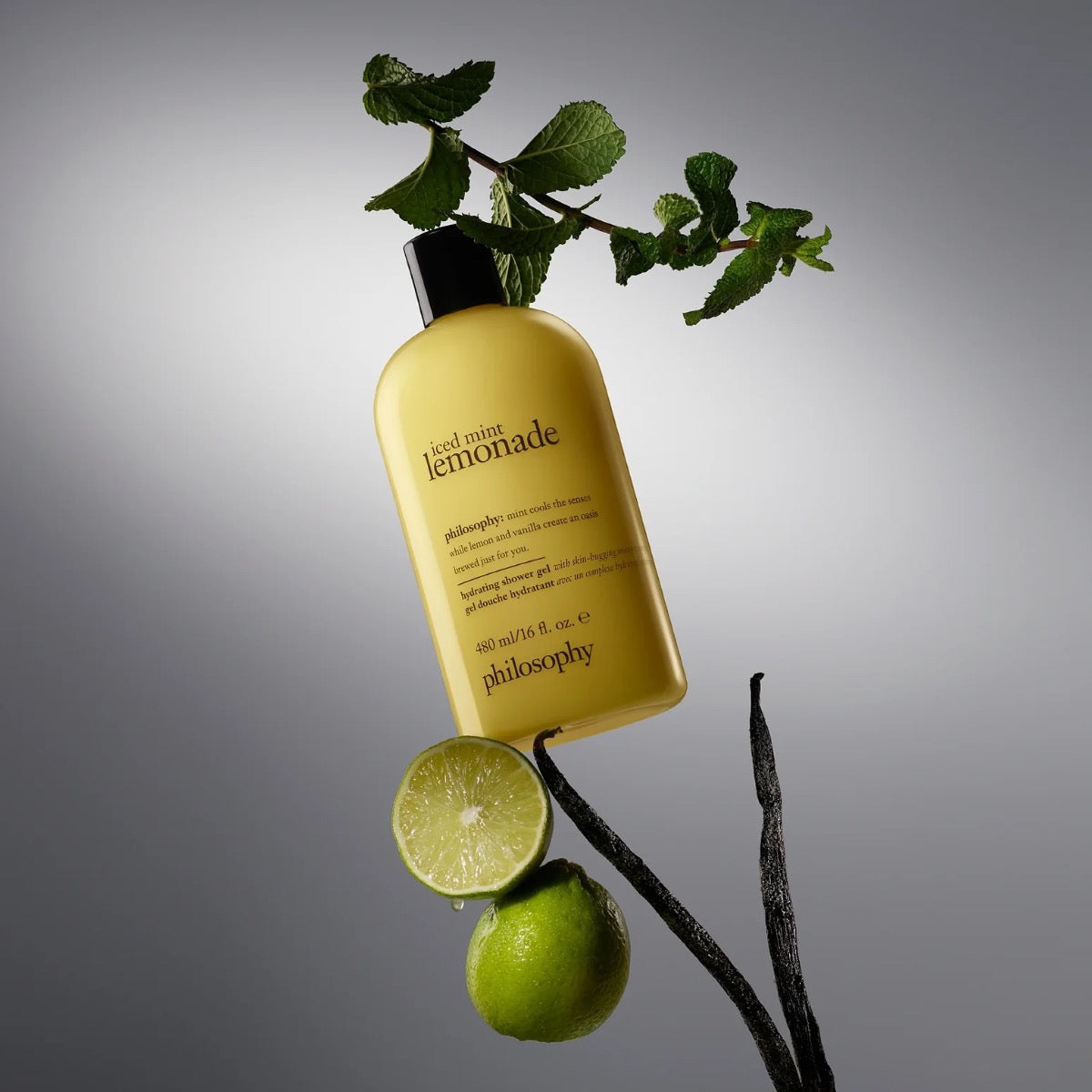 Philosophy iced mint lemonade shower gel bottle with fresh mint leaves and lime on a branch