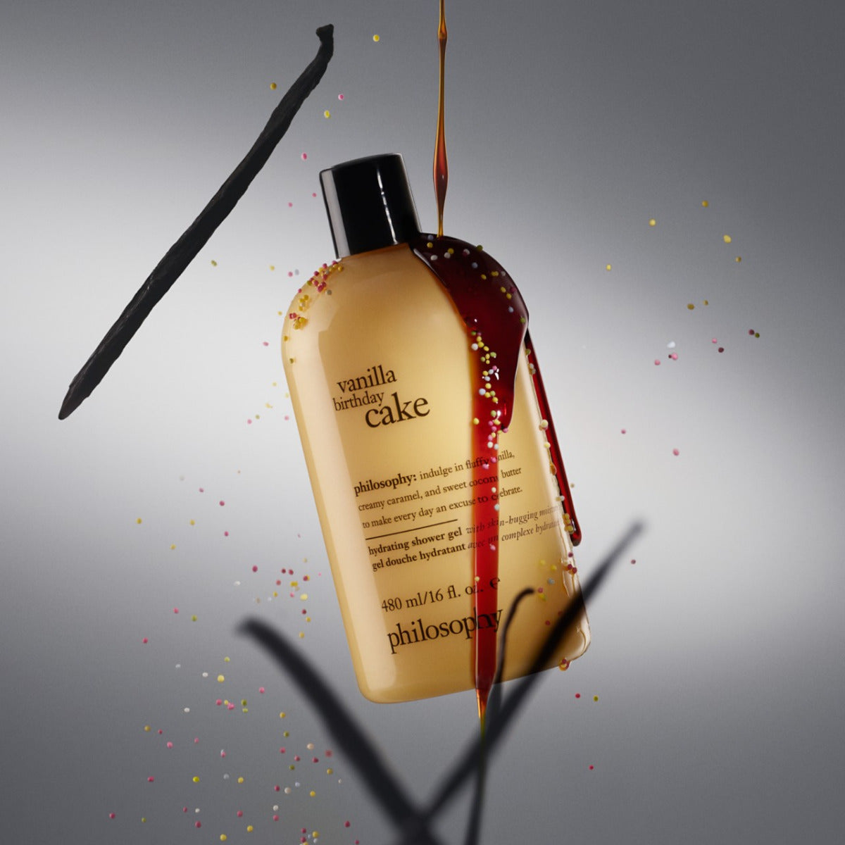 Philosophy vanilla birthday cake shower gel bottle with dripping syrup and vanilla bean on gray background