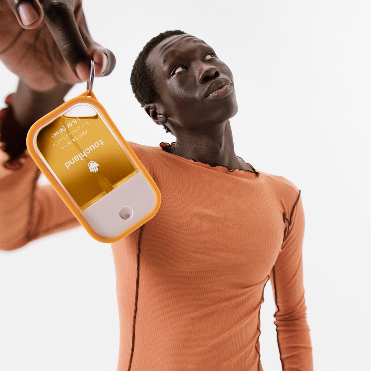 Touchland hand sanitizer mist in a portable orange case held by a person for easy access