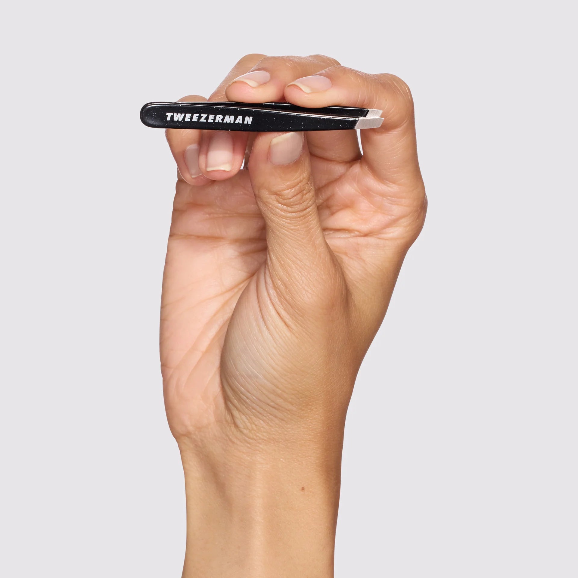 Tweezerman precision tweezer held in a hand for accurate eyebrow grooming