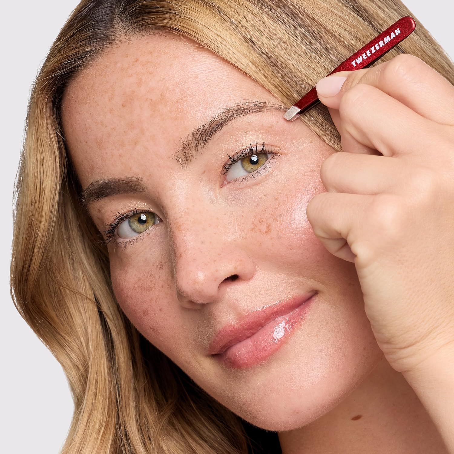 Tweezerman mini slant tweezer being used to shape eyebrows with precision