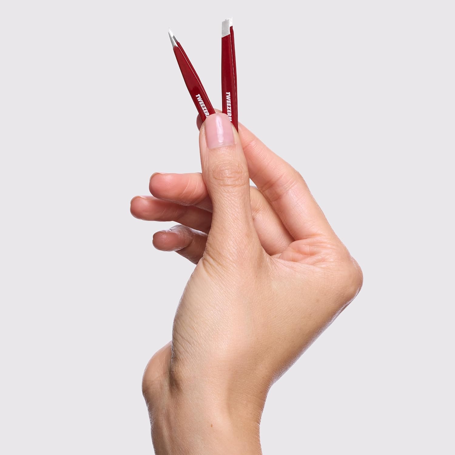 Tweezerman mini tweezer set in a hand, perfect for precision grooming and travel