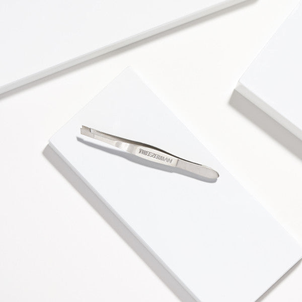 Tweezerman Slant Tip Tweezers in sleek silver design on a white surface for precision grooming