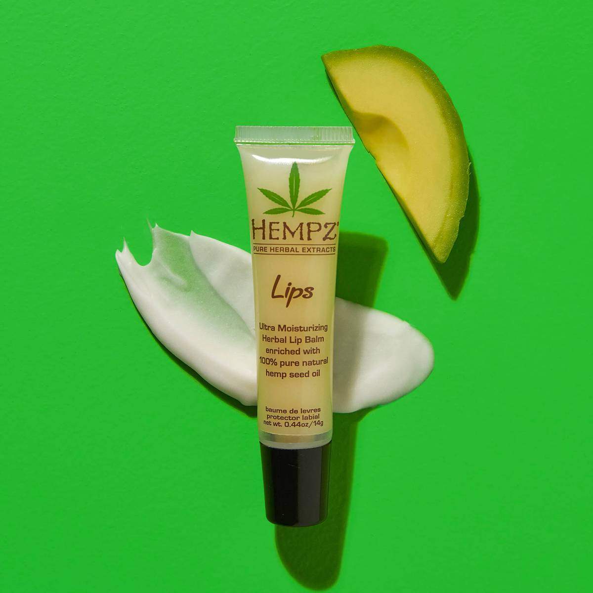 Hempz ultra moisturizing hemp lip balm tube with cream and avocado slice on green background