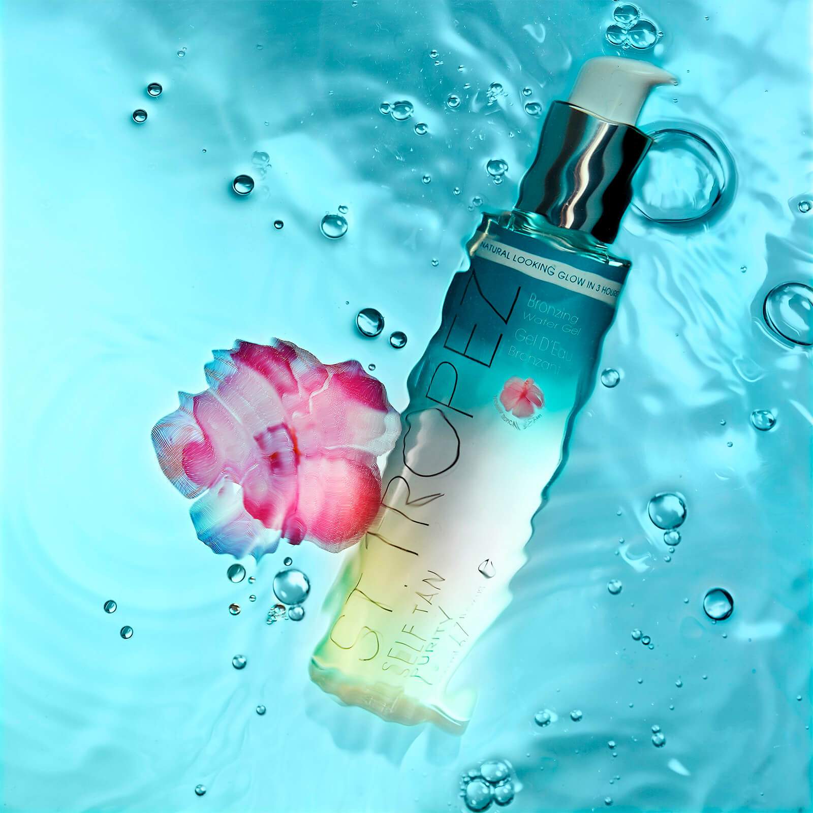 St. Tropez Purity Bronzing Water Gel bottle with pump floating in water with pink flower and bubbles