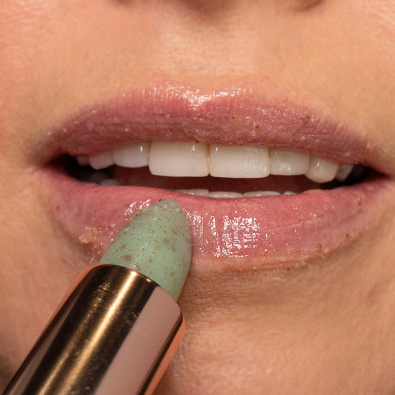 Karen Murrell close up of lips with green exfoliating stick applying natural lip scrub and exfoliant
