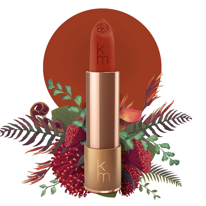 Karen Murrell natural lipstick warm terracotta red in gold tube with embossed km logo and botanical floral background