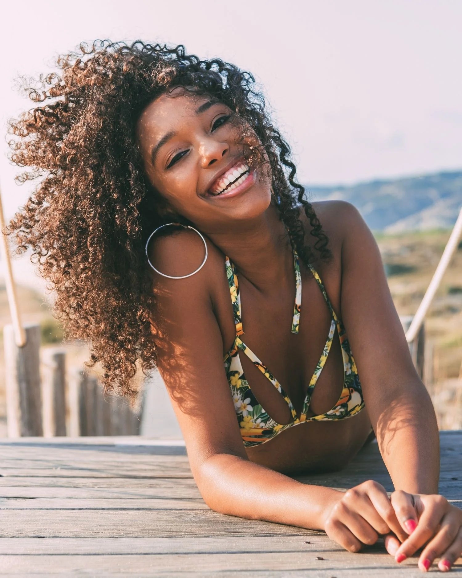Smiling woman with curly hair enjoying outdoor sunlight after using moisture repair shampoo