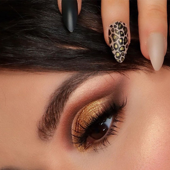 Close-up of hand showcasing Cala press on nails with leopard print, matte black, and nude designs