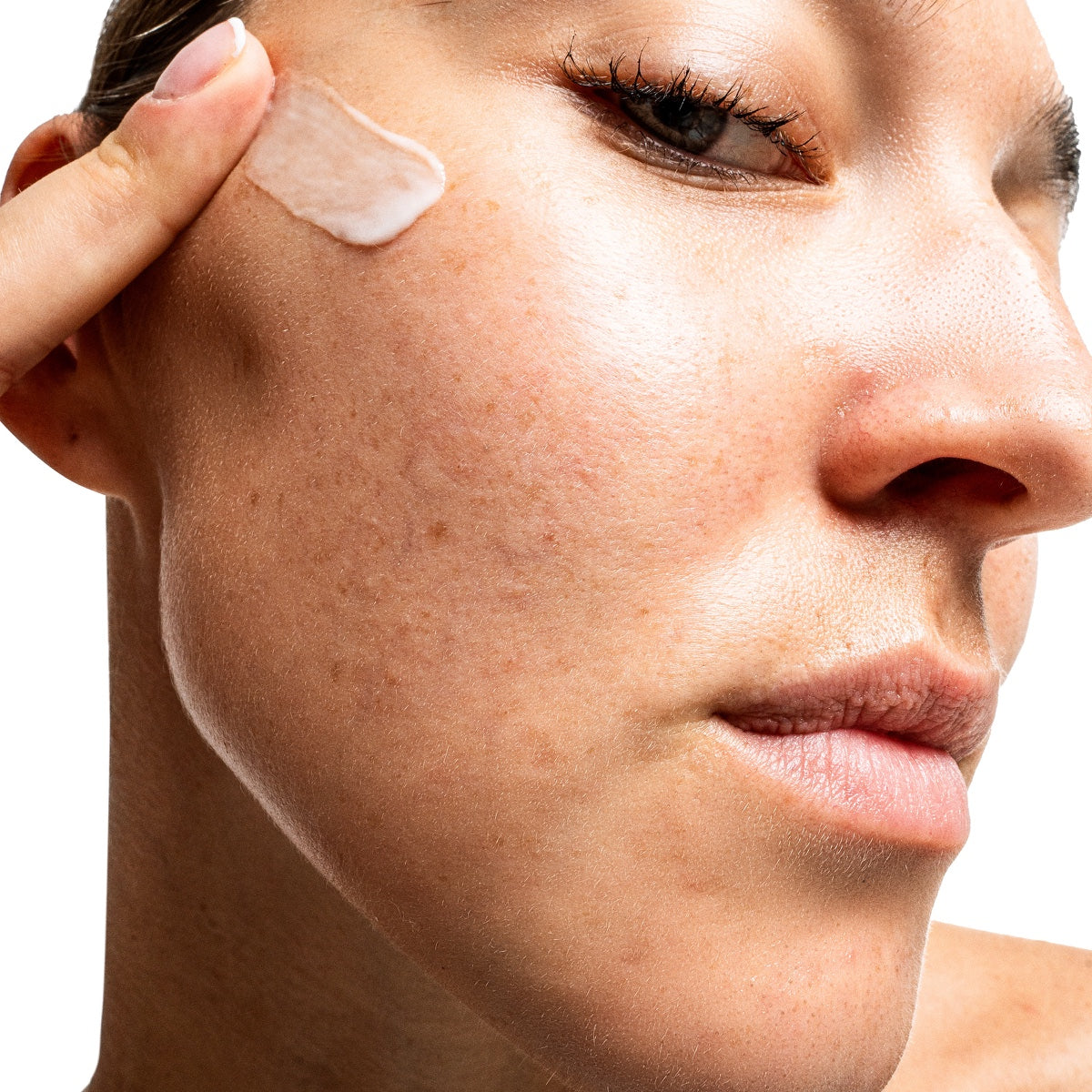 Woman applying cream to cheek showing textured skin and pores Allies of Skin 7 days to brighter skin kit for radiant skin