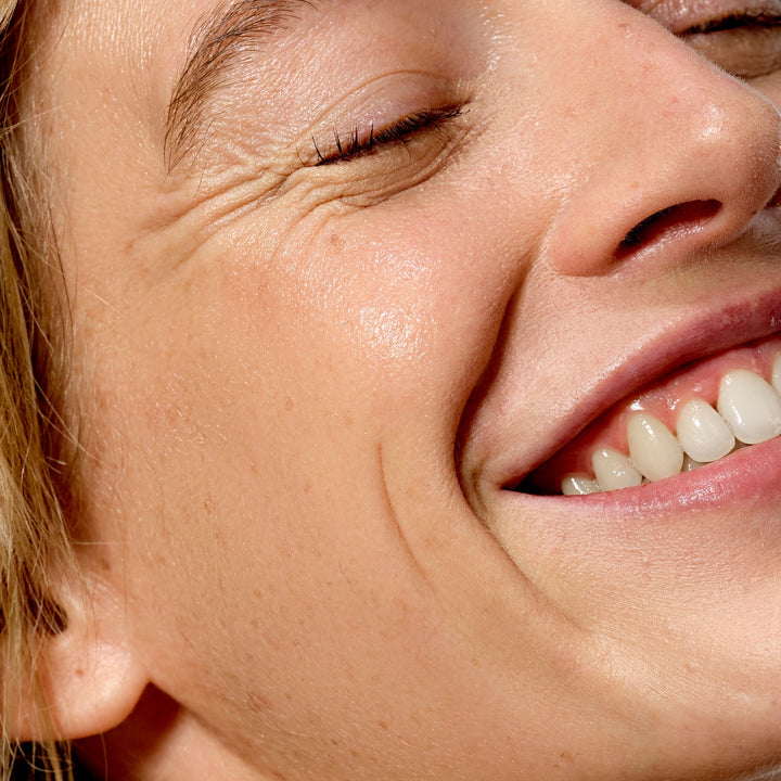 Close up of smiling woman showing radiant skin using Allies of Skin 7 days to brighter skin kit for glow