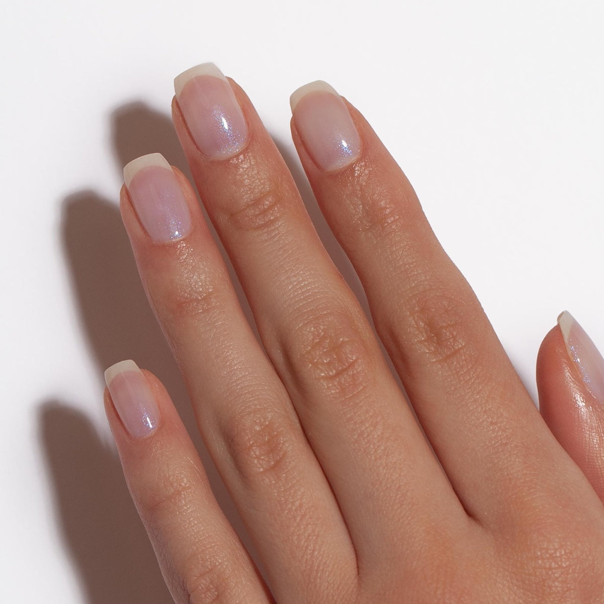Dermelect Luminous Brightener review showing a natural hand with glossy iridescent sheer polish on clean short nails