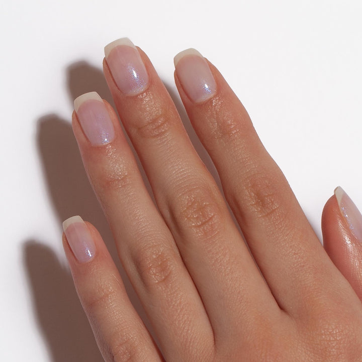 Dermelect Luminous Brightener review showing a natural hand with glossy iridescent sheer polish on clean short nails