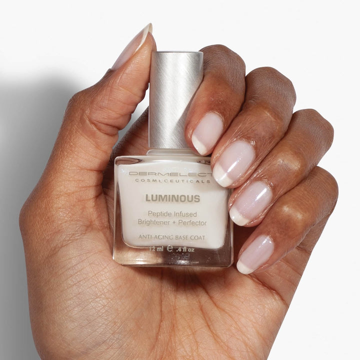 Dermelect Luminous Brightener review Hand with French manicure holding Dermelect Luminous bottle