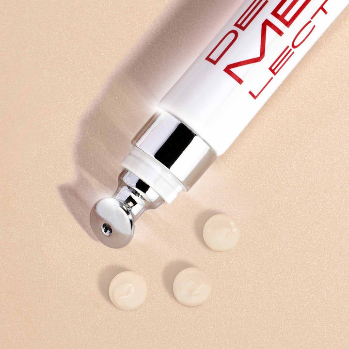 Dermelect Revitalite for dark circles tube with metal eye applicator and three cream swatches on beige background
