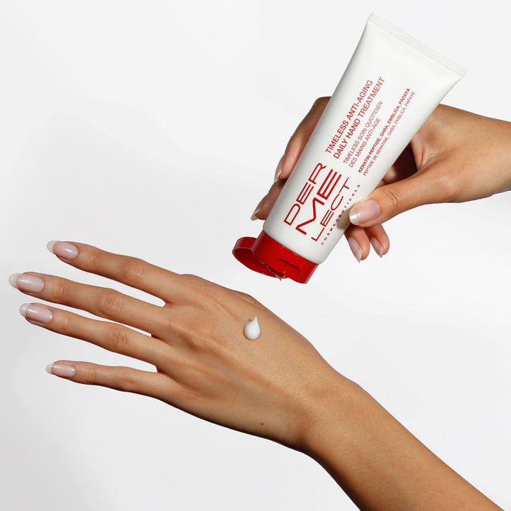 Dermelect Timeless Daily Hand Treatment tube dispensing cream onto back of manicured hands