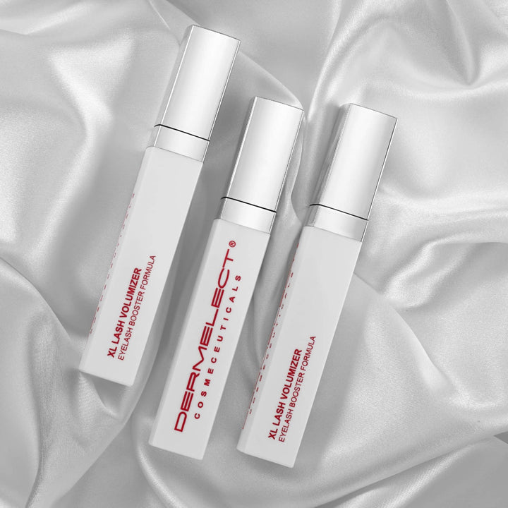 Dermelect XL Lash Volumizer three white tubes on silver satin background cosmetic lash booster