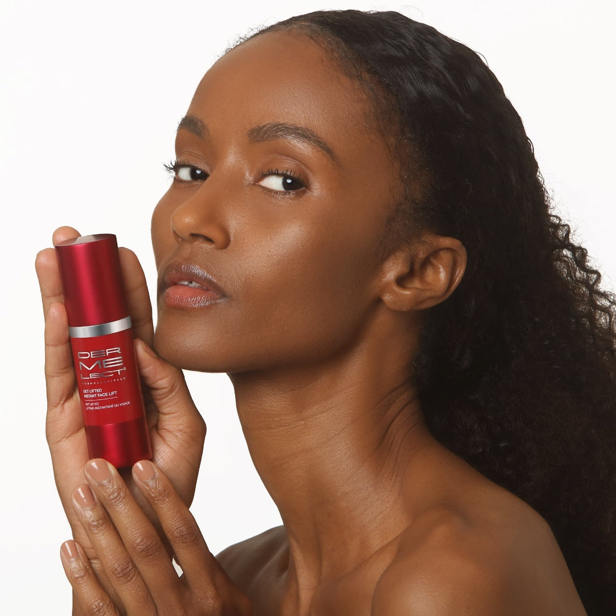 Dermelect instant face lift serum in red pump bottle held by model with glowing brown skin