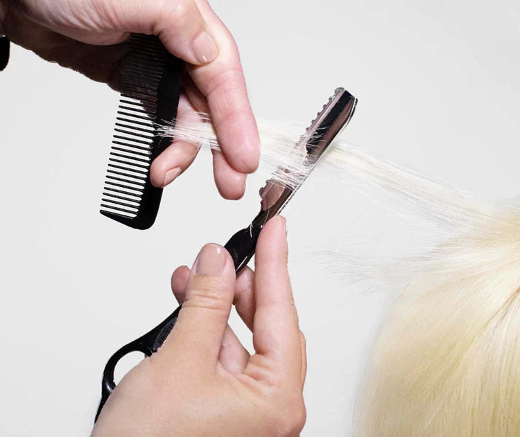 Feather razor blade being used to texture hair with a comb for a professional hairstyle
