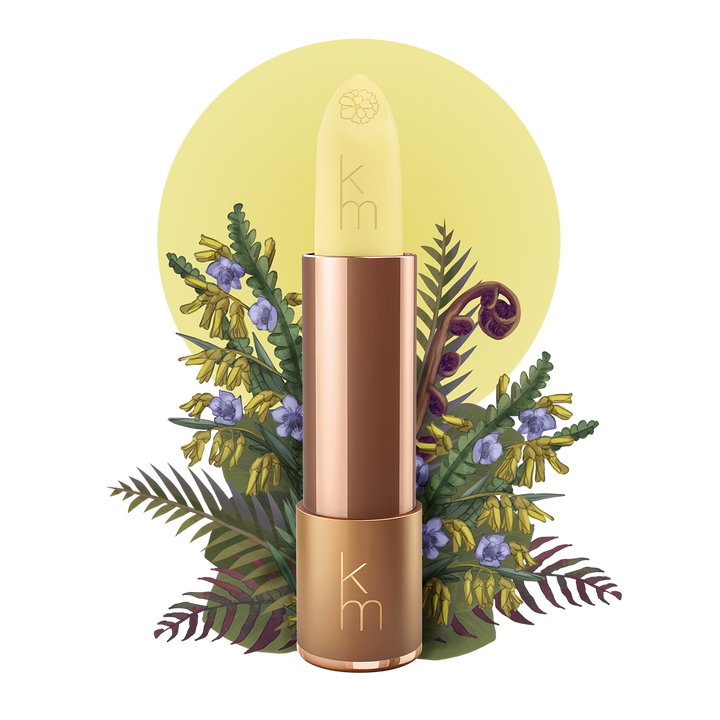 Karen Murrell Natural Moisture Stick in pale yellow balm with rose gold tube and botanical floral background