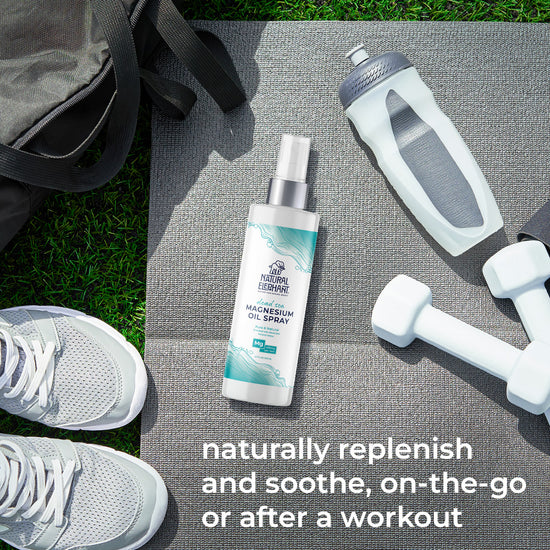 Natural Elephant Dead Sea magnesium oil benefits spray bottle on workout mat with dumbbells and water bottle