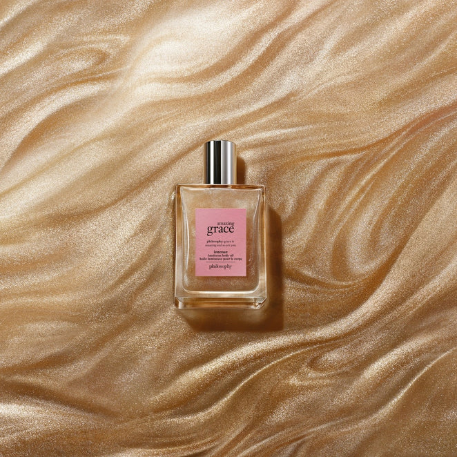 Philosophy Amazing Grace body oil bottle with silver cap on shimmering gold fabric background