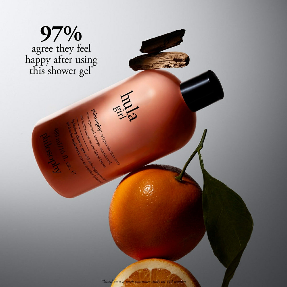 Philosophy Hula Girl shower gel bottle with orange fruit and wood pieces on gray background