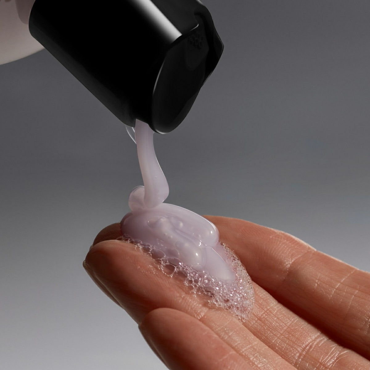 Philosophy lavender hydrating shower gel with creamy texture pouring into a hand with bubbles