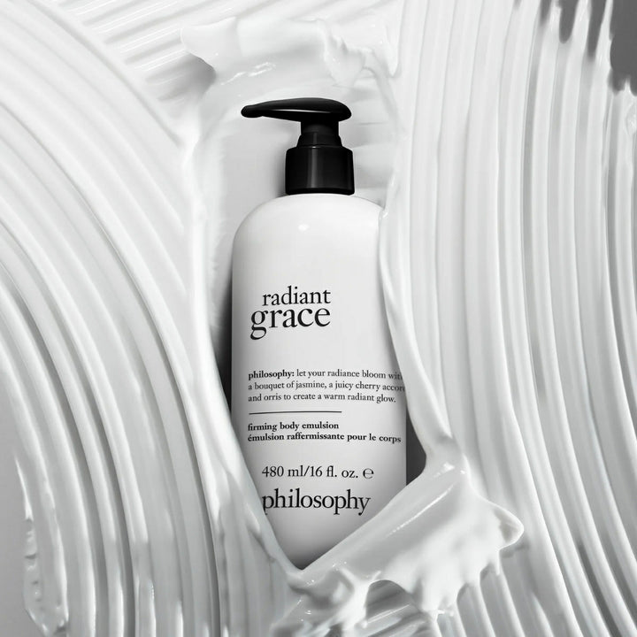 Philosophy Radiant Grace body emulsion bottle surrounded by creamy white lotion texture