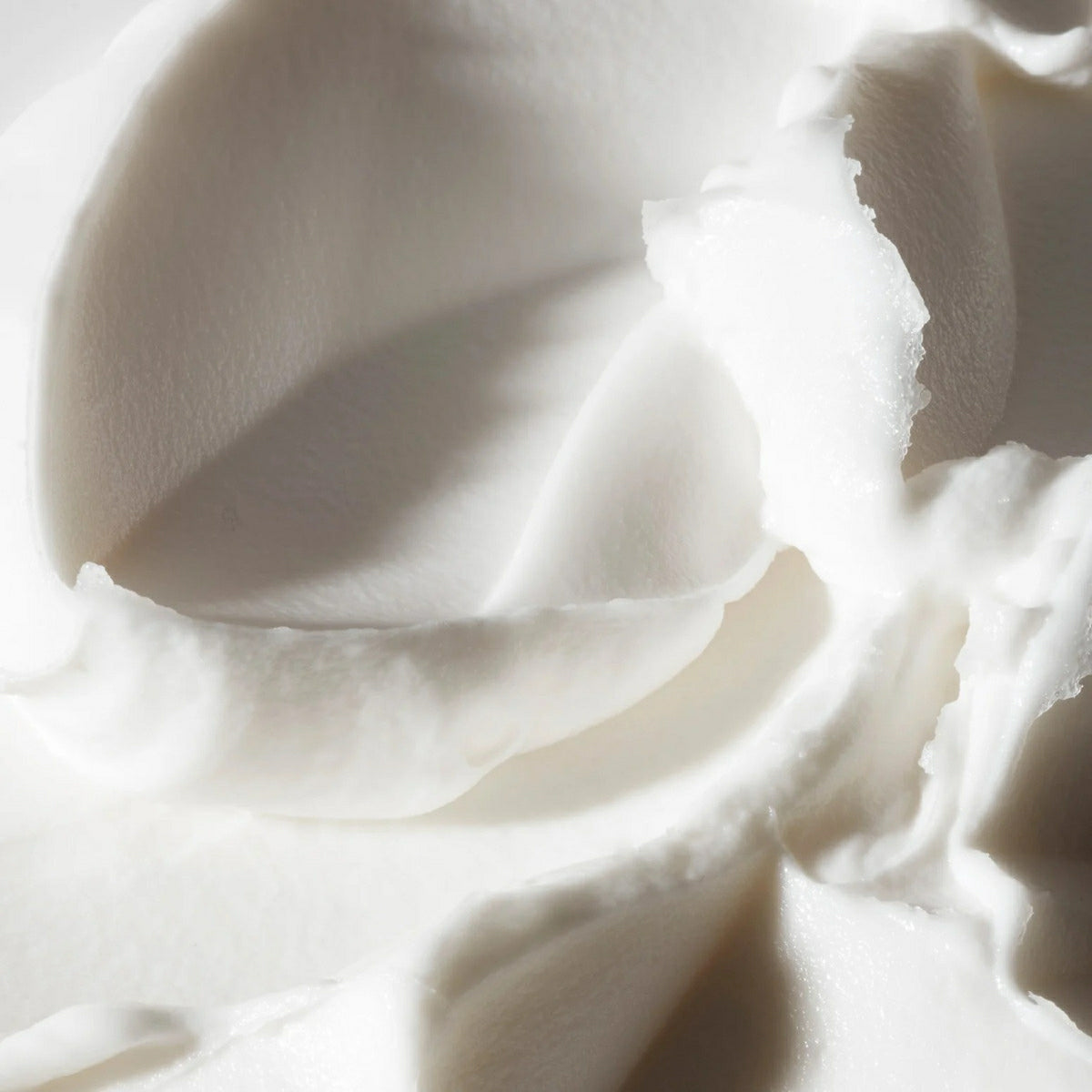 Close-up texture of Philosophy Radiant Grace body cream showing smooth white moisturizer