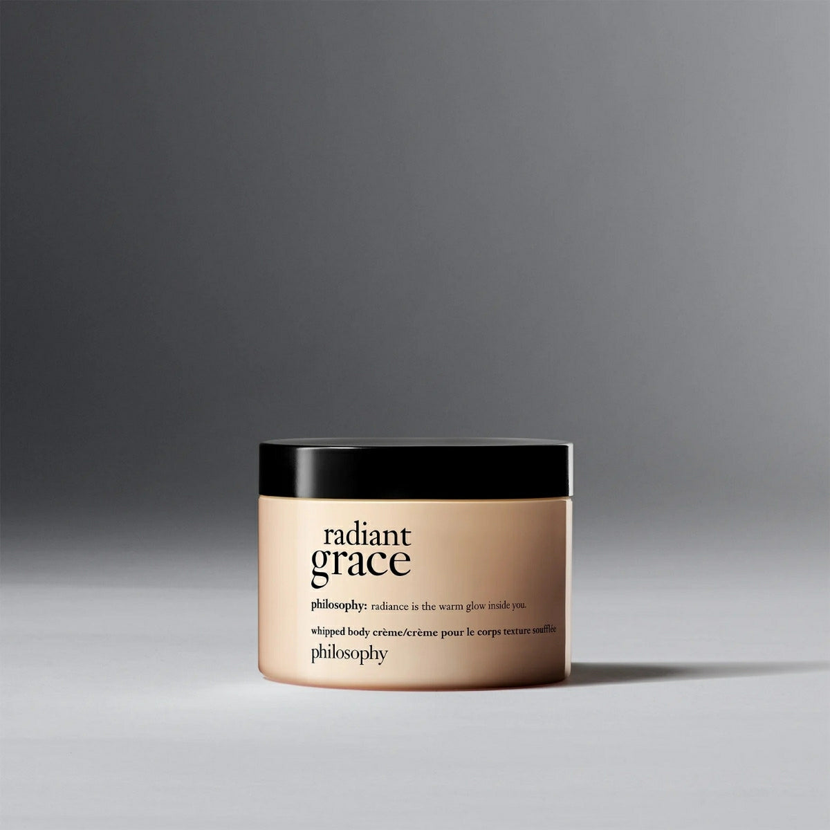 Philosophy Radiant Grace body cream in a beige jar with black lid on gray background