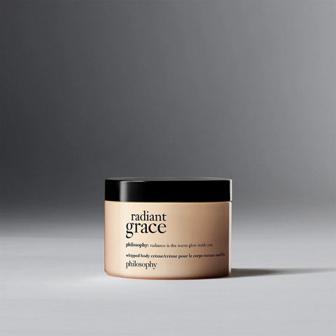Philosophy Radiant Grace body cream in a beige jar with black lid on gray background