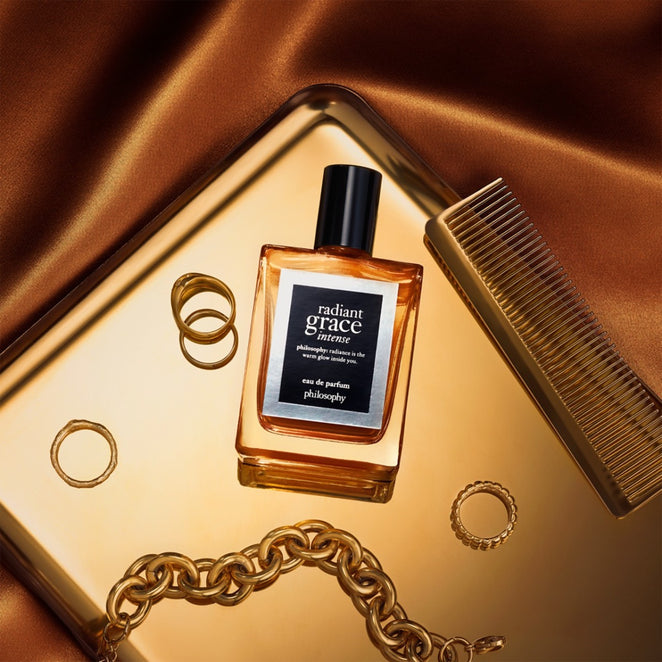 Philosophy Radiant Grace Intense eau de parfum bottle with gold rings, chain, and comb on golden tray